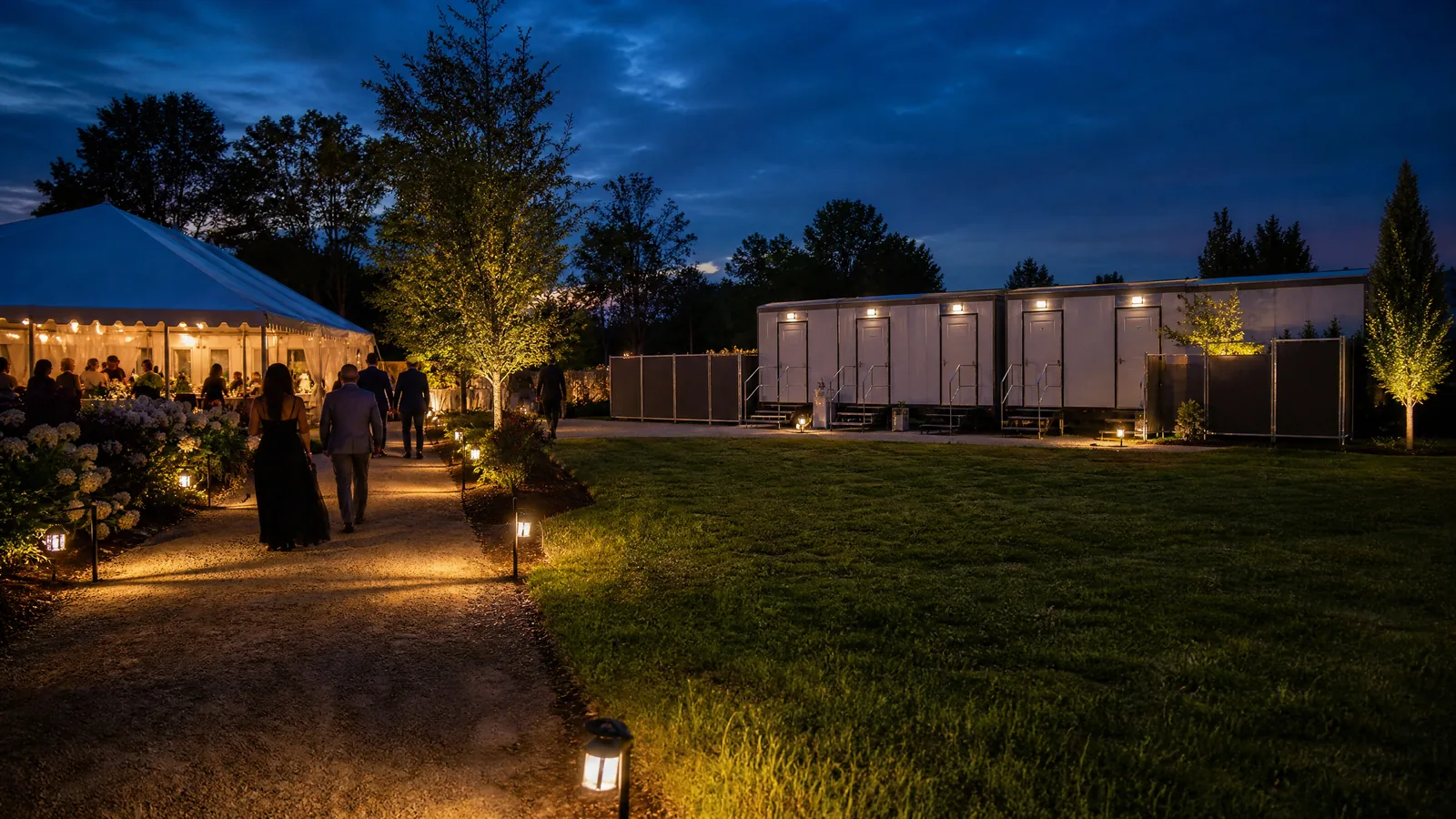 A portable restroom zone with safe path lighting at an evening outdoor event.